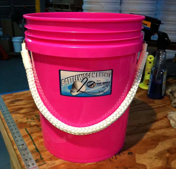 Pink bucket with a visible brand label on a wooden surface