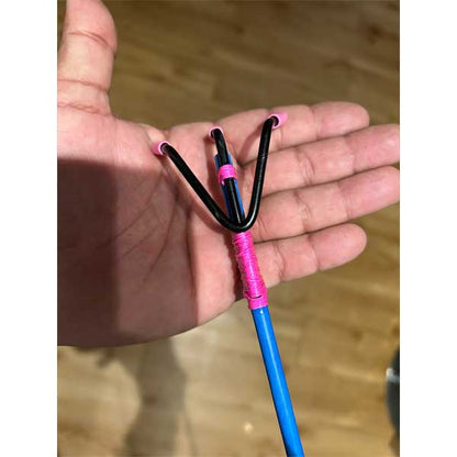 Hand holding a blue and pink slingshot against a wooden background