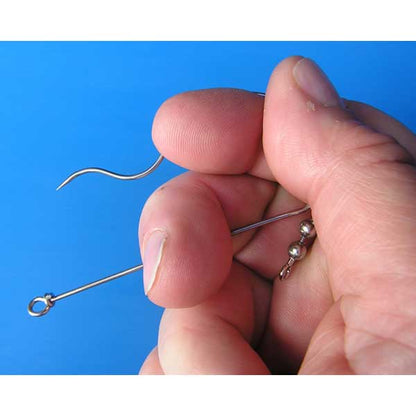 Hand holding a small metal descender hook against a blue background