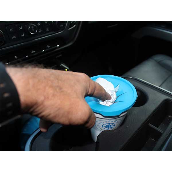 Hand using a blue lid to open a container in a car's cup holder.