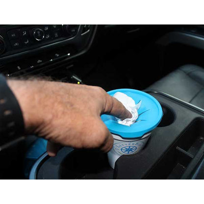 Hand using a blue lid to open a container in a car's cup holder.