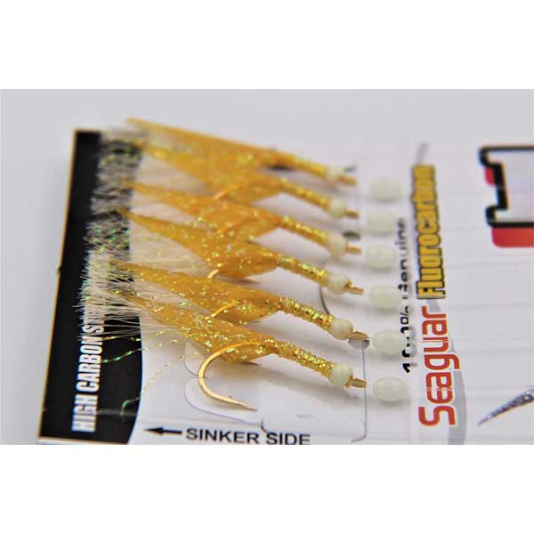 Packaged fishing lures with gold and white colors on a white background